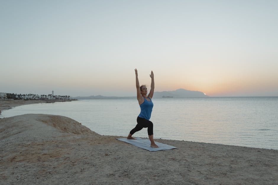 Yoga practitioner performing warrior pose at sunset